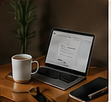 Laptop und Kaffeetasse auf einem aufgeräumten Schreibtisch